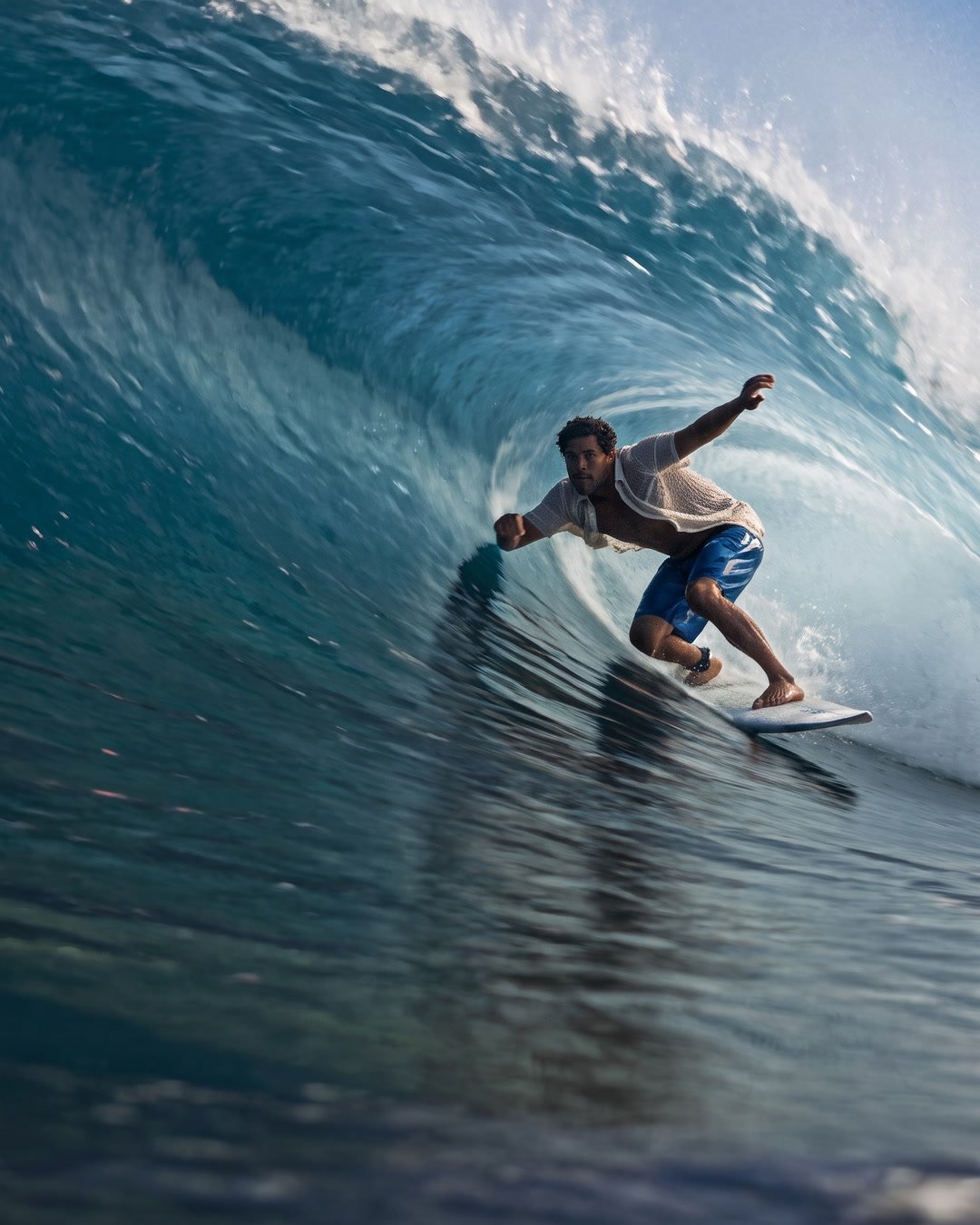 A surfer crouched deep in the barrel of a breaking wave