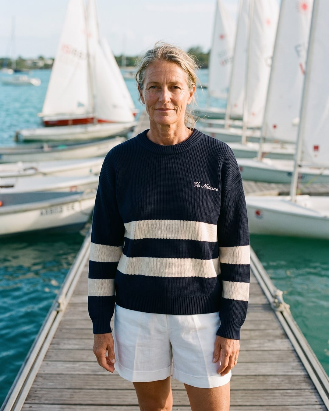 A sailor on a pontoon at Grand Baie in the navy and ecru Mooring Stripe Crew and white Esplanade Linen Shorts